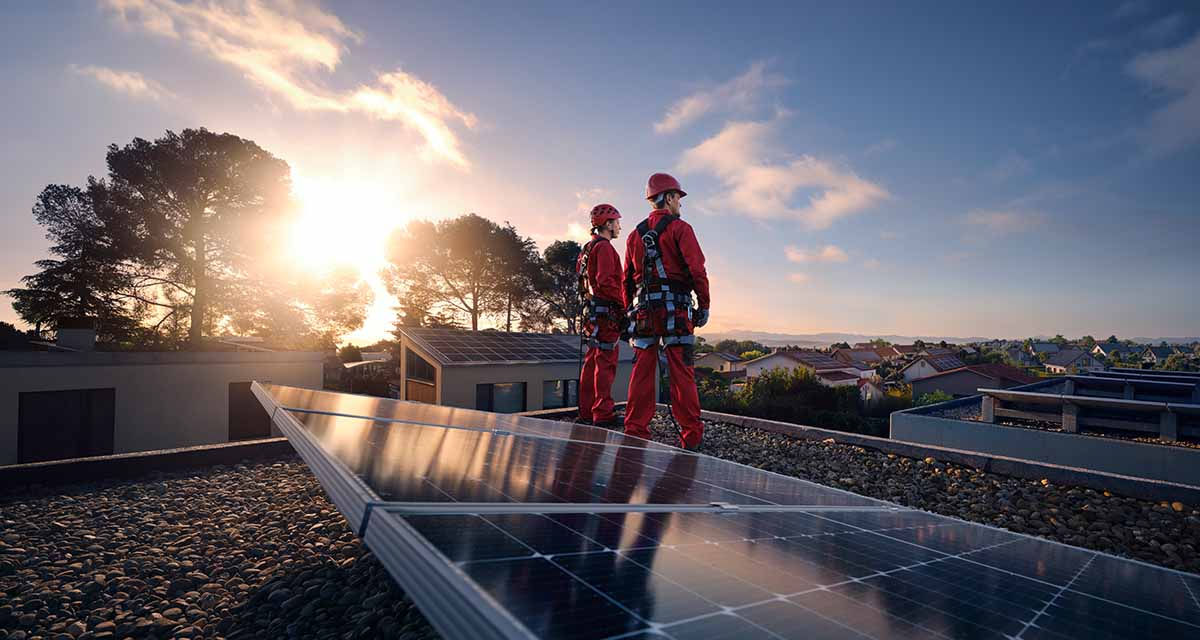 Due tecnici controllano un impianto fotovoltaico, rispettando tutte le norme sulla sicurezza sul lavoro