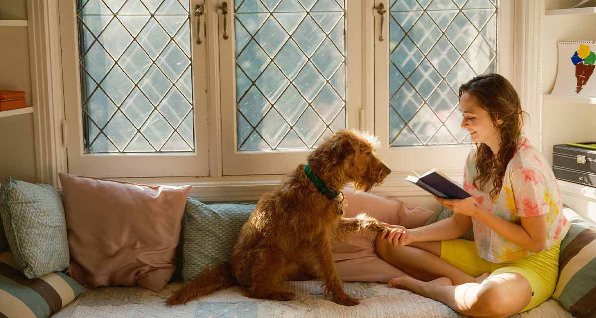 Una ragazza col cane legge un libro su un divano e si gode il comfort domestico garantito da un corretto monitoraggio energetico